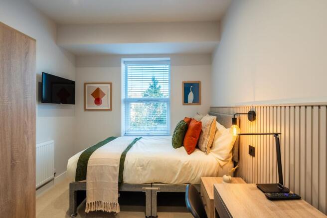 Bright, neatly styled bedroom with a comfortabl...