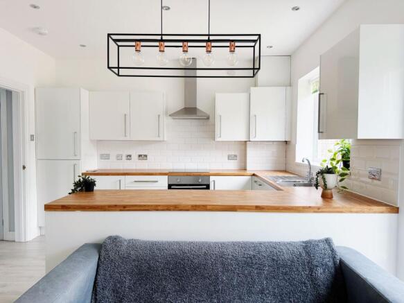 Bright modern kitchen with white cabinetry, woo...