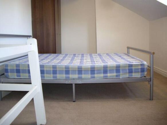 Simple, tidy bedroom with a metal single bed an...