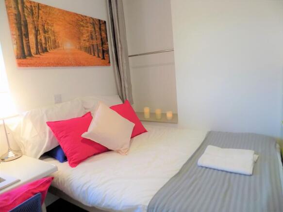 Bright, neatly made bedroom with crisp white be...