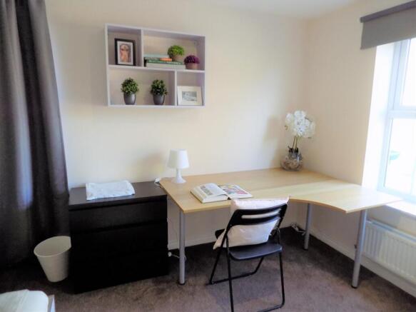 Bright, neatly furnished bedroom corner with a ...