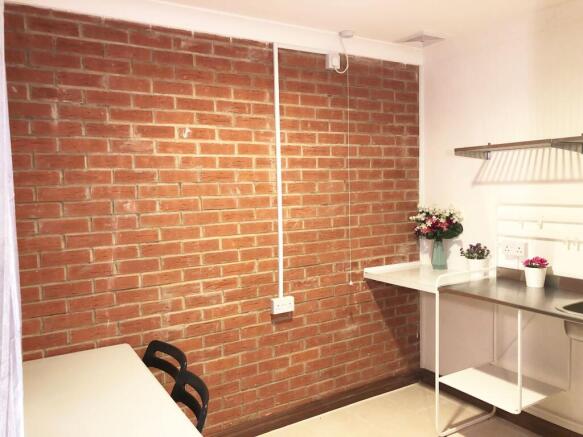 Bright, modern kitchenette with exposed brick f...