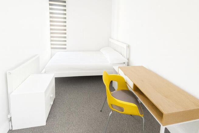 A bright, minimalist single bedroom with white ...