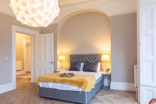 Bright, elegant bedroom with a tufted grey head...