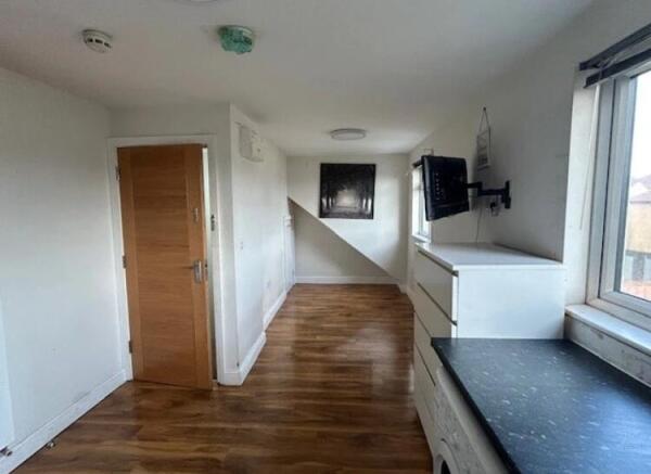 Long, bright communal workspace with wood-effec...