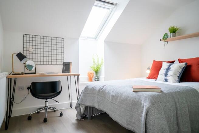 A bright and inviting double bedroom with a sty...