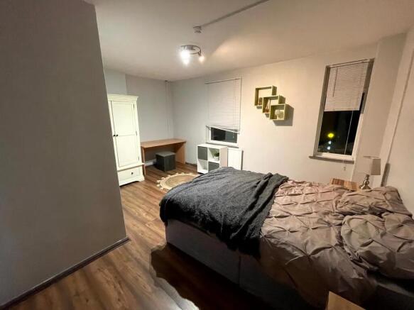 A cozy double bedroom featuring wood-effect flo...