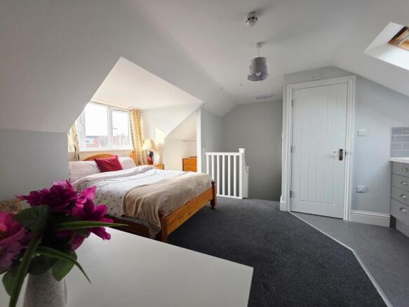 A spacious, well-lit bedroom featuring a large ...