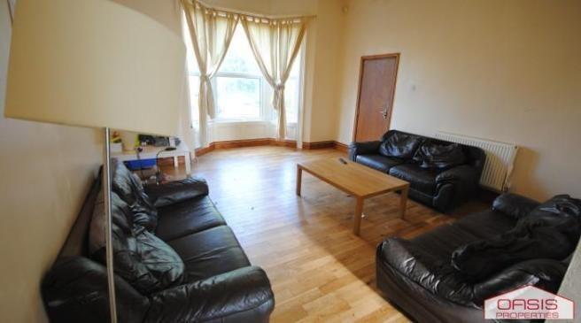 Spacious communal living room with hardwood flo...
