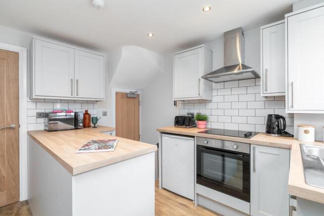 Bright modern kitchen with light cabinetry, woo...