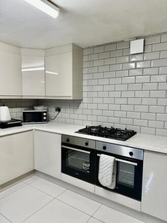 A clean and modern kitchen featuring white tile...