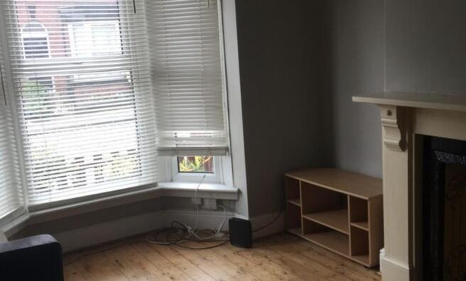 Bright living room with a large bay window lett...