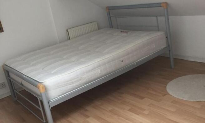 Bright, simply furnished bedroom with a metal d...