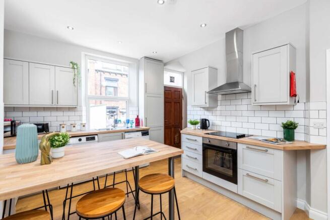 Bright, modern kitchen with white cabinetry, su...