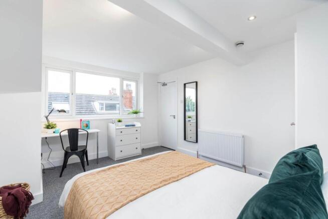 Bright, modern bedroom with vaulted ceiling, la...