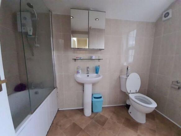 Bright tiled bathroom with a bathtub and shower...