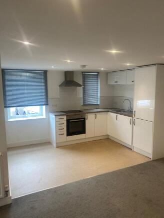 Modern open-plan kitchen with white cabinets, i...
