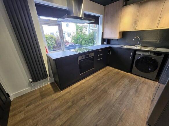 Modern kitchen with sleek black cabinets and wo...