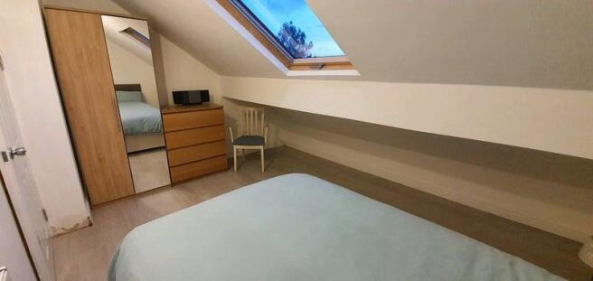A cozy double bedroom featuring a sloped ceilin...