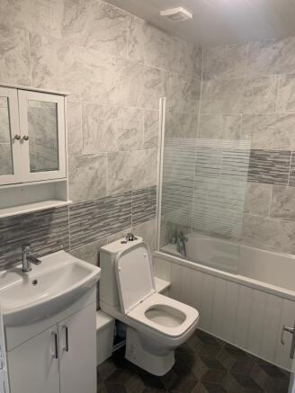 A modern bathroom suite featuring a white sink ...