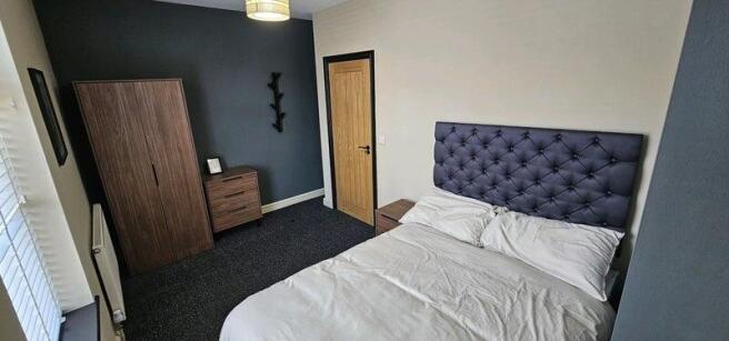 A cozy double bedroom featuring a tufted headbo...