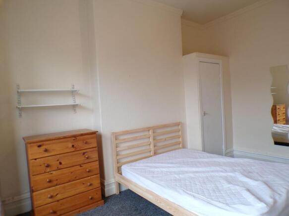 A cozy double bedroom featuring a wooden bed fr...