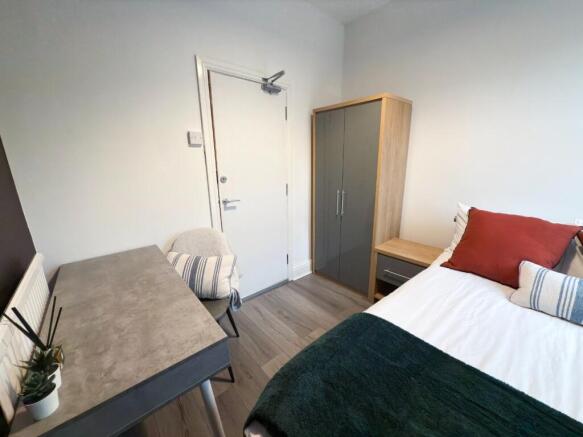 A cozy single bedroom featuring a comfortable b...