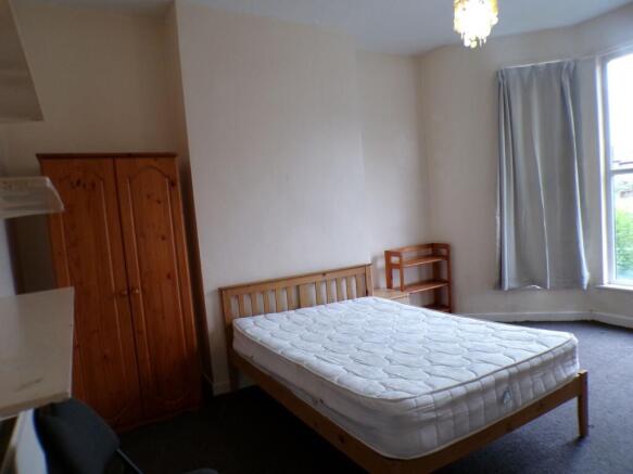 Bright double bedroom with a wooden bed frame a...