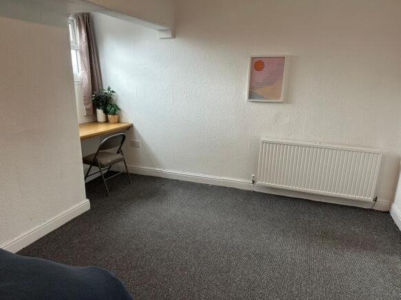 A bright, cozy bedroom with a small desk under ...