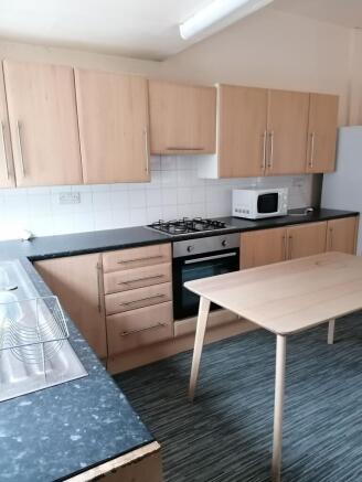 Modern fitted kitchen with light wood cabinets,...