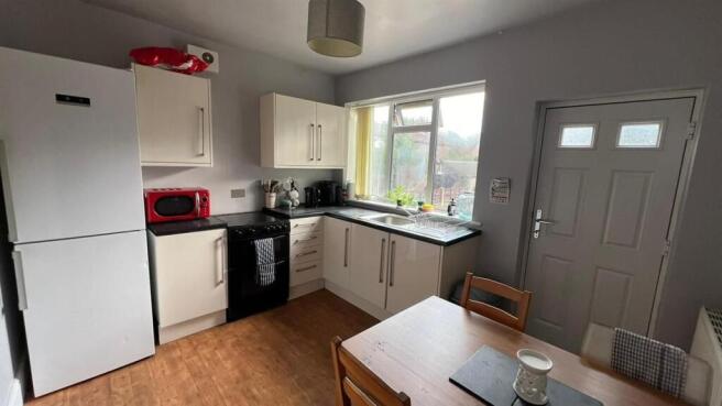 A well-lit kitchen area with white cabinets, a ...