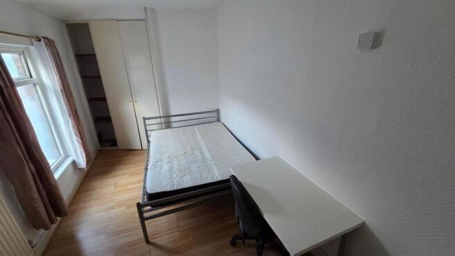 A tidy bedroom featuring a standard bed frame w...