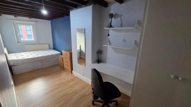 A well-lit bedroom featuring a comfortable bed,...