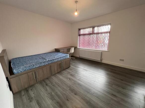A spacious and well-lit single bedroom featurin...
