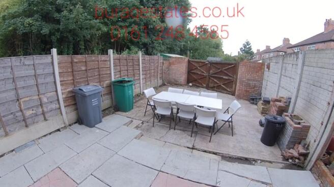 A private enclosed garden featuring a paved pat...