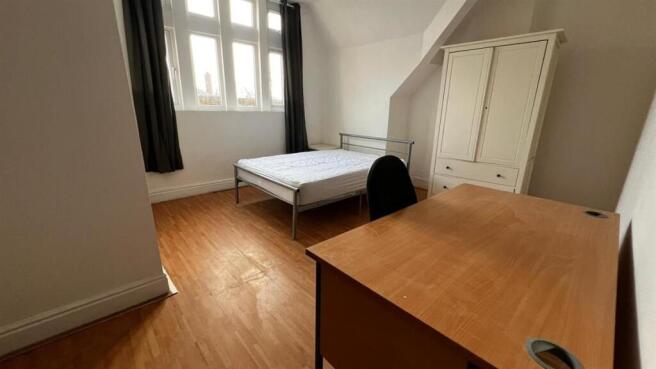 A bright double bedroom featuring a wooden floo...