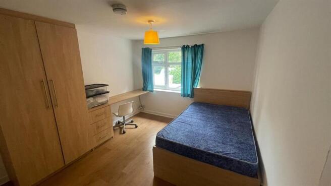 A cozy single bedroom featuring a spacious bed,...