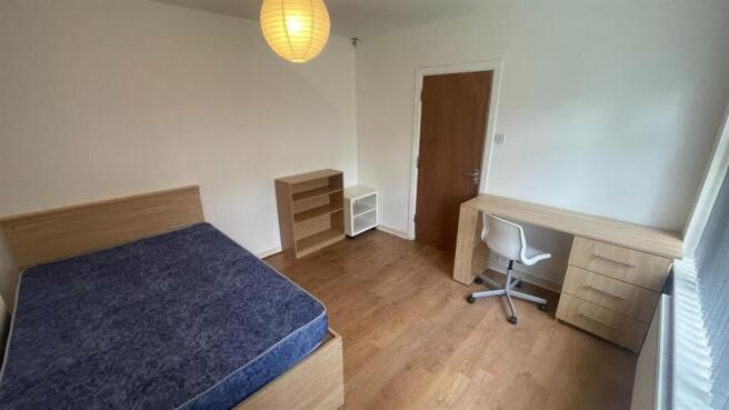 A clean and well-lit bedroom with a large bed a...