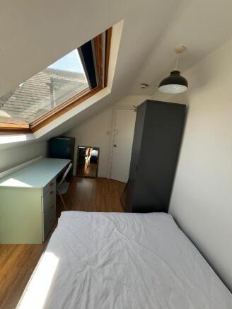 Bright and cozy single bedroom with a sloped ro...