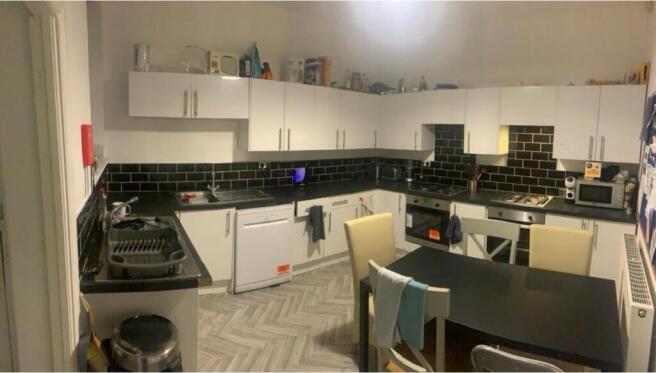 Modern kitchen area featuring white cabinets, a...