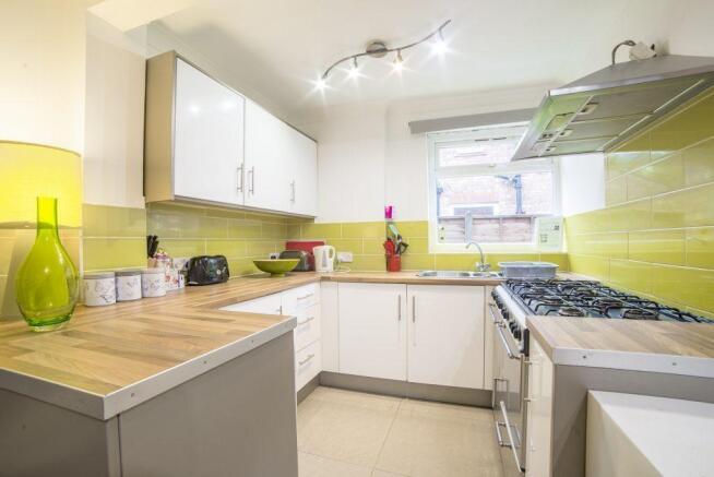 Modern galley kitchen with white cabinets, ligh...
