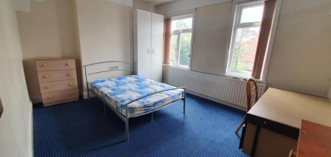 A bright double bedroom featuring two large win...