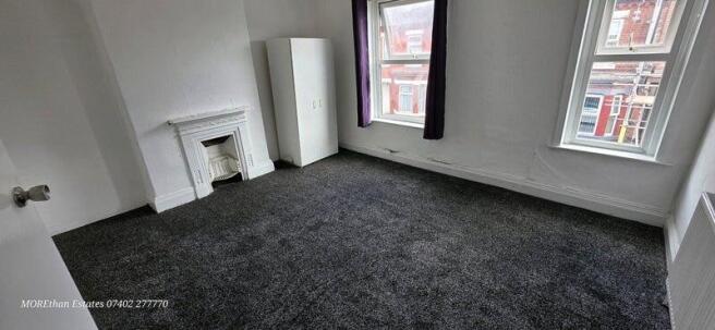 Bright master bedroom featuring two large windo...