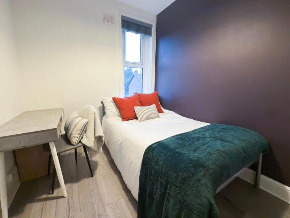 Cozy, neatly styled single bedroom with a comfo...