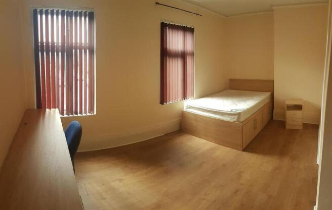 Bright, simply furnished bedroom with two windo...