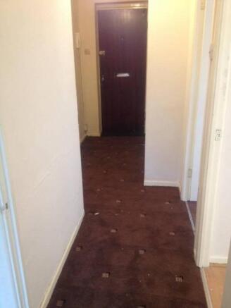 Narrow entrance hallway with patterned carpet l...