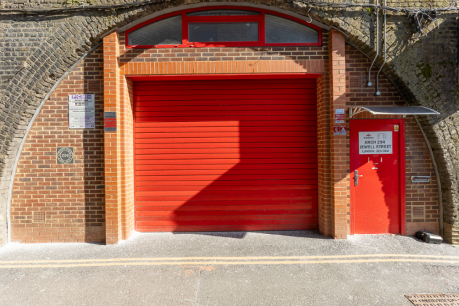 The front of an arch, with high level glazing, an open electric roller shutter entrance big enough for vehicle access, and a pedestrian door.