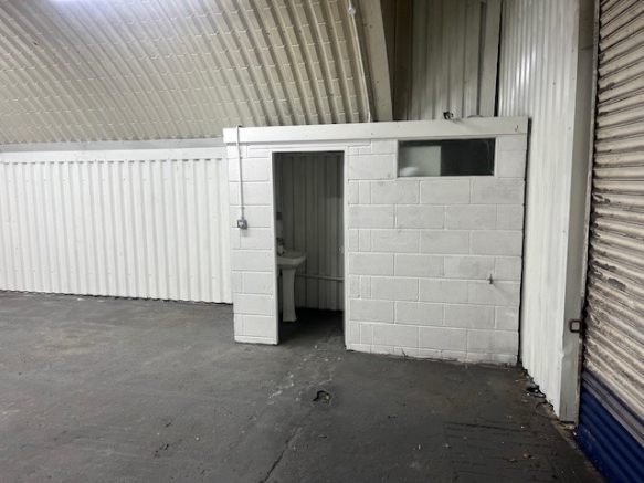 An empty arch with white lining and a WC cubicle to the front.