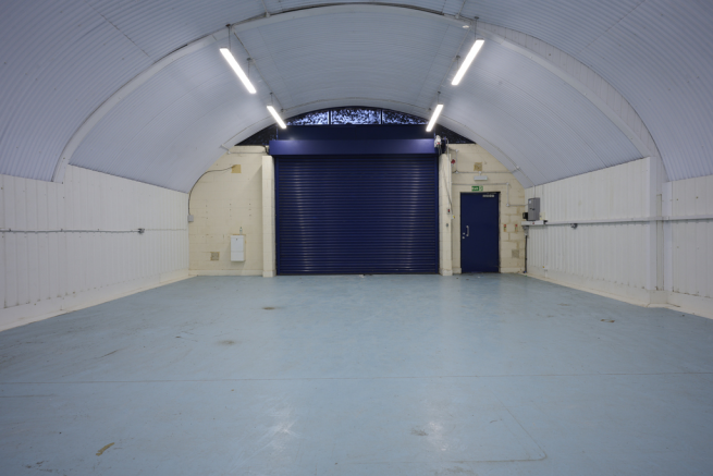 An empty arch with lining, facing the front electric roller shutter entrance, which is closed.