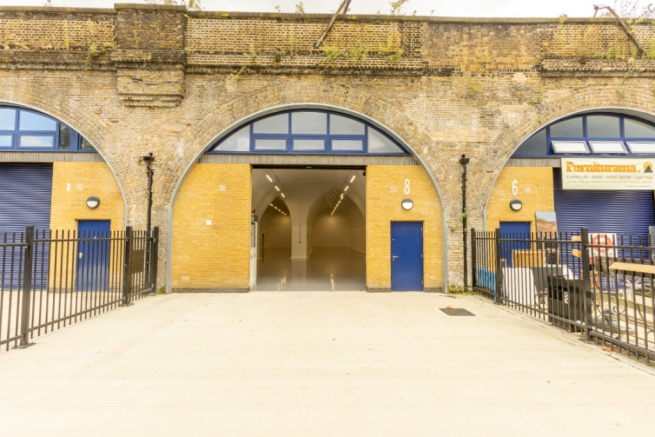 The front of an arch, with high level glazing, an open electric roller shutter entrance big enough for vehicle access, and a pedestrian door.